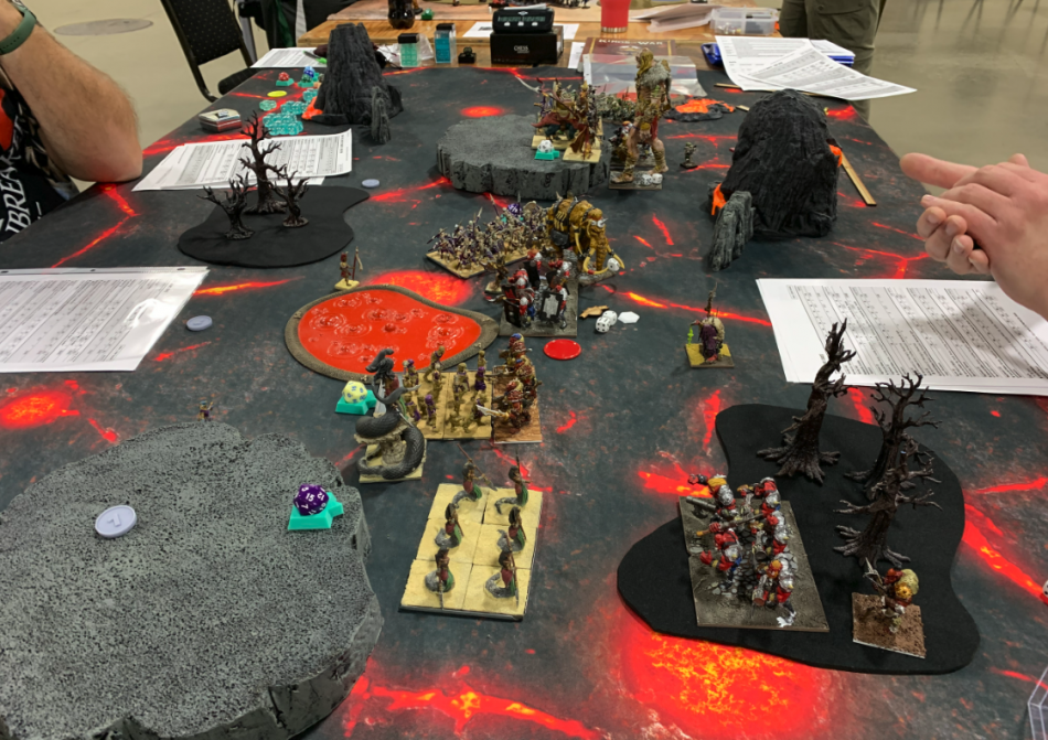 A game of Kings of War played on a lava themed table